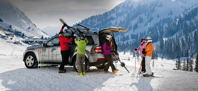 car in the snow with family getting skis from ski rack